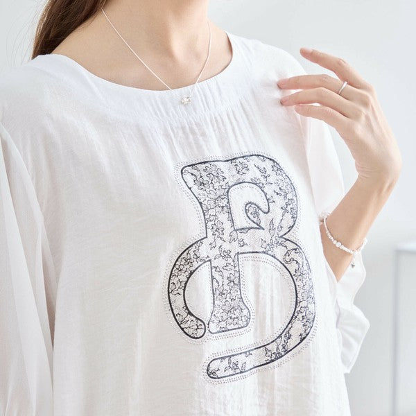 アルファベット柄のホワイトTシャツを着たモデルの正面アップ