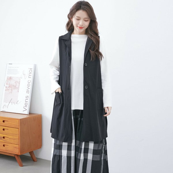 ブラックのロングベストを着用したモデル モノトーンコーデで上品な印象のフロントカット
