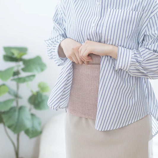 女性が前を閉じた腹巻を着用しながら立っている様子