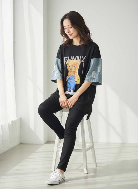 Mikonosublue Storeのビジュー付きベアプリントとダメージデニム袖が特徴の黒いドッキングTシャツを着た女性