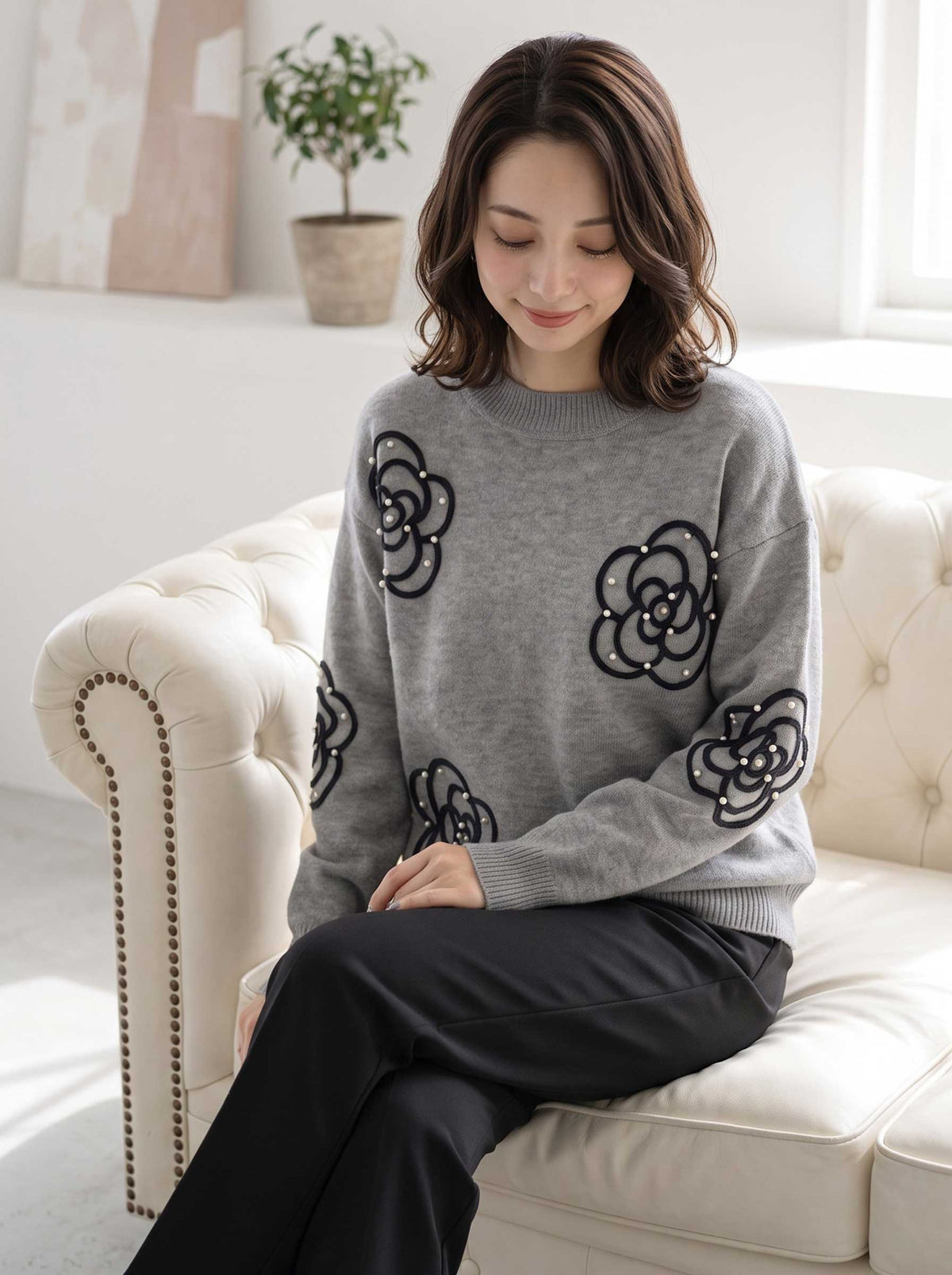 Mikonosublue Storeのグレーのニットプルオーバー。カメリア柄のコード刺繍とパール、ビジューが施された上品な長袖セーター。