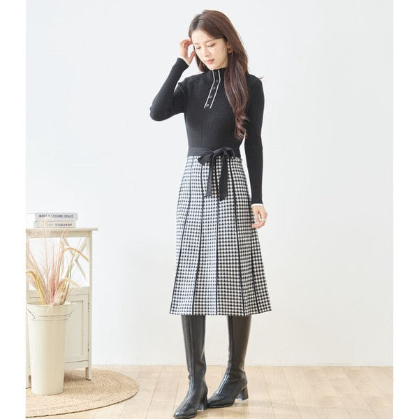Mikonosublue Storeの黒いリブニットとチェック柄スカートのドッキングワンピース。ウエストリボン付きでハイネックのフェミニンな秋冬スタイル