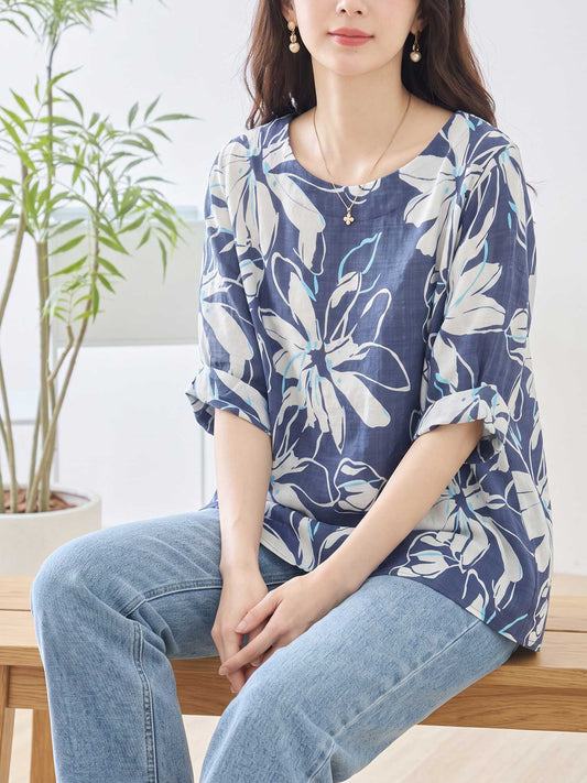 Mikonosublue Storeのネイビー地に白い大きな花柄がプリントされた綿100%のゆったりとしたドルマンスリーブトップスを着用した女性