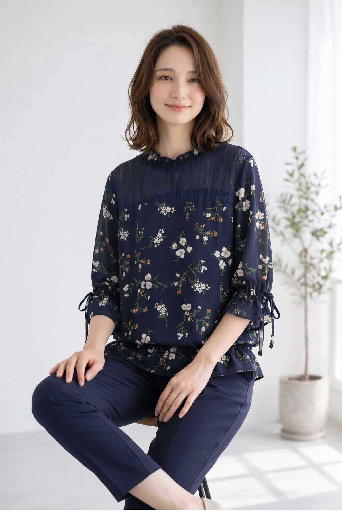 Mikonosublue Storeのネイビー花柄ジョーゼットブラウス。デコルテのレースと袖口のリボンが上品な七分袖トップス。