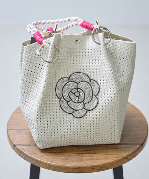 Mikonosublue Storeのホワイトメッシュミニバッグ。キラキラ輝くカメリアモチーフとカラフルなロープハンドルが特徴で、自立するマチ広デザイン。