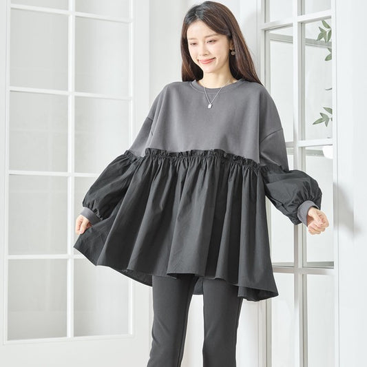 フレア袖とティアードデザインが印象的なブラウスを着用したモデル(微笑み)