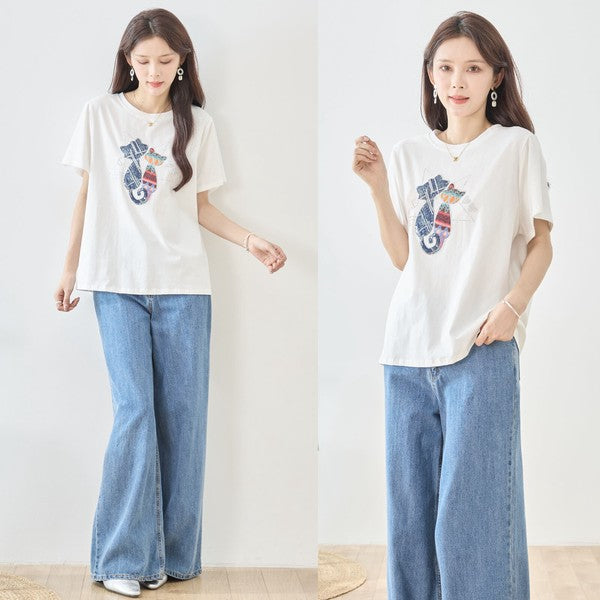 ホワイトTシャツの前面全体。シンプルながらも華やかな猫モチーフが、コーディネートに洗練された印象をプラス。