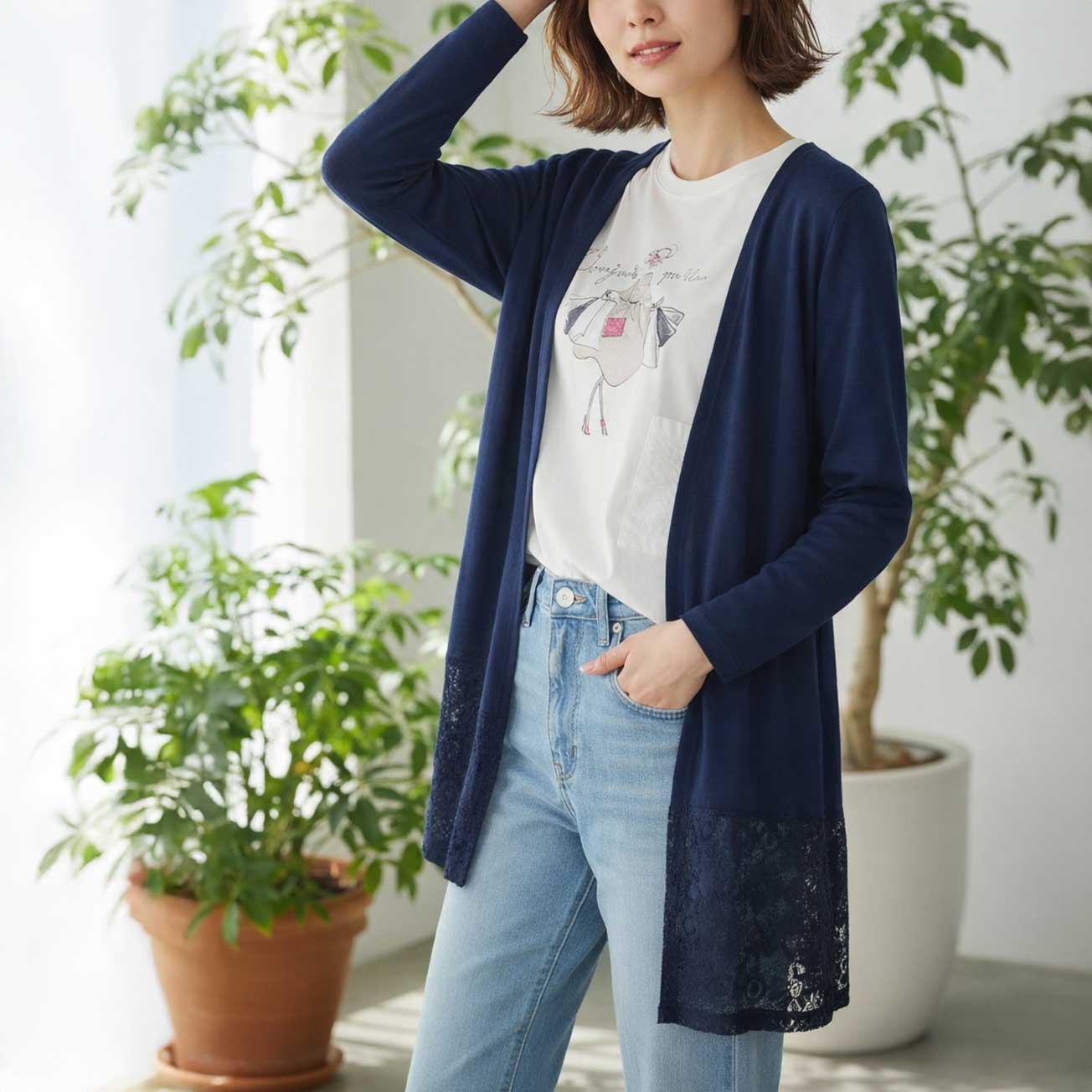 ネイビーの裾レーストッパーカーディガン。知的な印象を与える深みのあるカラーで、体型をすっきり見せる視覚効果も。