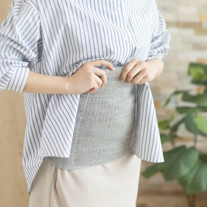 女性がストライプシャツの上から腹巻を巻いている様子