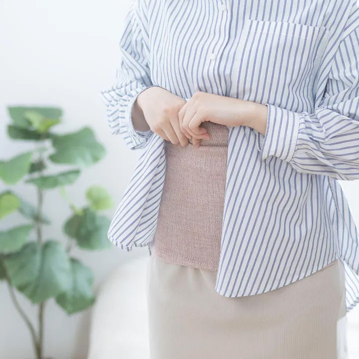 女性が前を閉じた腹巻を着用しながら立っている様子