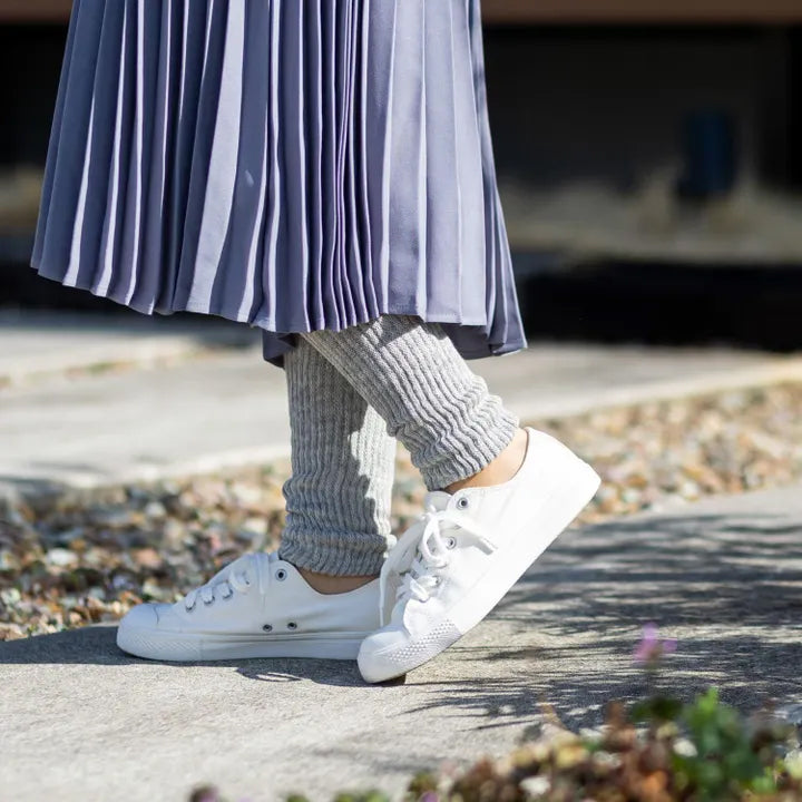 グレーのレッグウォーマーを着用して外を歩く女性（白スニーカー）