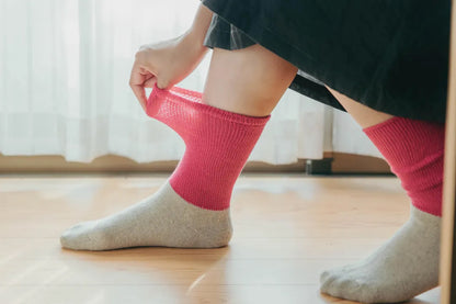 ピンクのソックスを足に通す様子（ナチュラルな室内光）