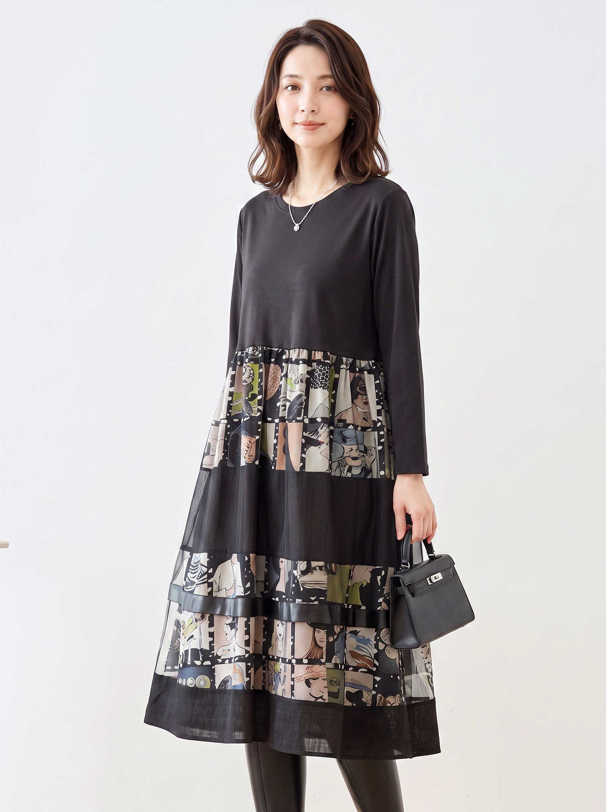 Mikonosublue Storeの異素材切替ロングワンピース。黒の無地トップスとアートなコラージュ柄スカートのドッキングデザインで、ゆったりとしたシルエットが特徴。