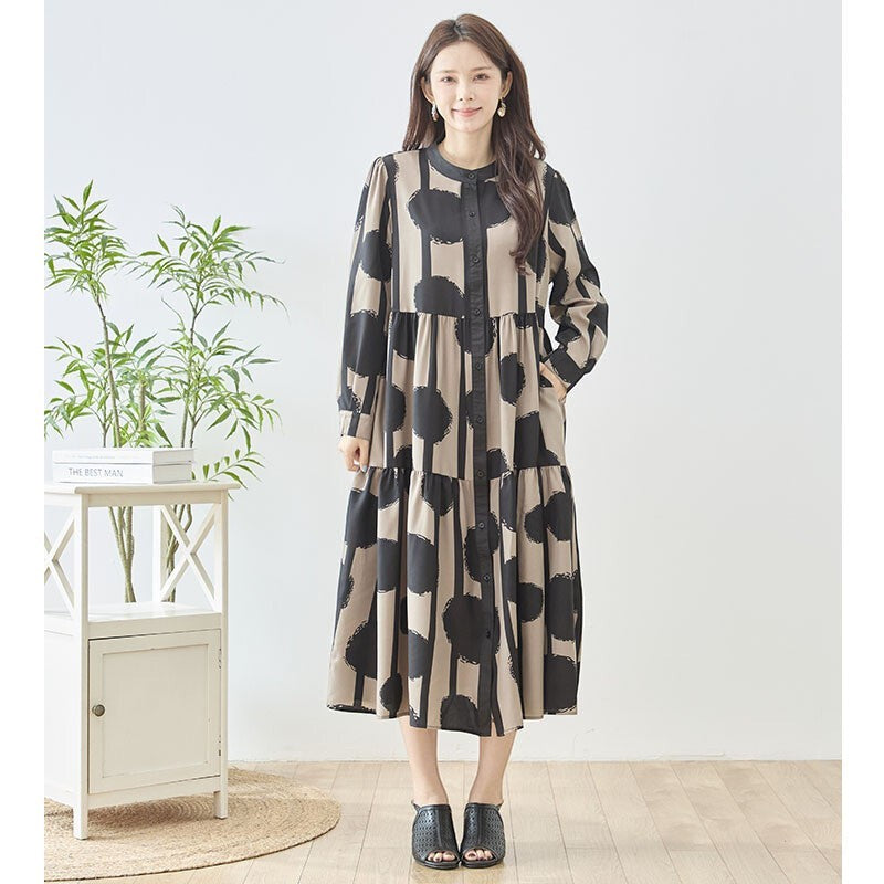 Mikonosublue Storeのアートドット柄ティアードシャツワンピース。ベージュと黒のモダンな総柄で、スタンドカラーとゆったりしたシルエットが特徴。
