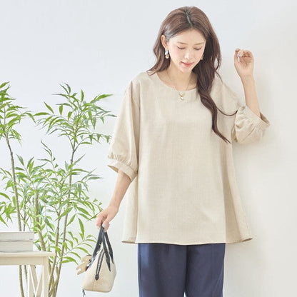 Mikonosublue Storeのベージュの5分袖Aライントップス。ゆったりとしたシルエットで二の腕をカバーし、さらりとした素材感が夏に最適。
