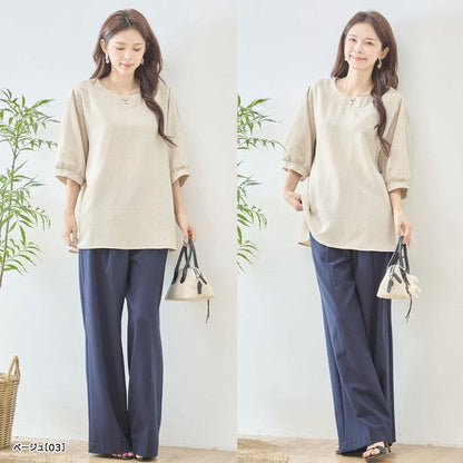 Mikonosublue Storeのベージュの5分袖Aライントップス。バックフリルとファスナーが特徴で、ゆったりとしたシルエットが体型をカバーします。
