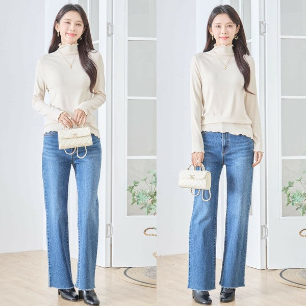 Mikonosublue Storeのベージュのハイネックメロウフリルリブカットソーを着用し、デニムパンツと合わせた女性の全身コーディネート