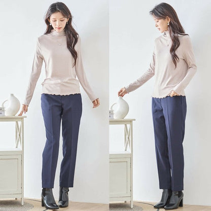 Mikonosublue Storeのベージュのメロウフリルハイネックリブカットソーを着用した女性の全身コーディネート