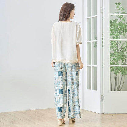 Mikonosublue Storeのゆったりとしたベージュの半袖トップスを着用し、後ろ姿を見せる女性