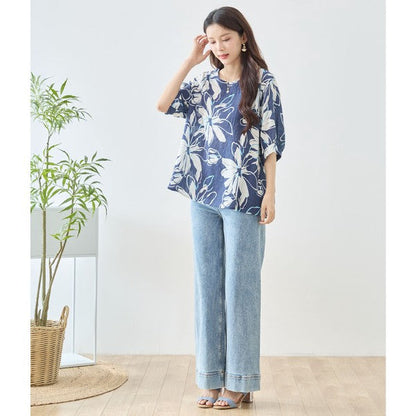Mikonosublue Storeのネイビー地に白い大きな花柄がプリントされた綿100%のドルマントップスを着用した女性