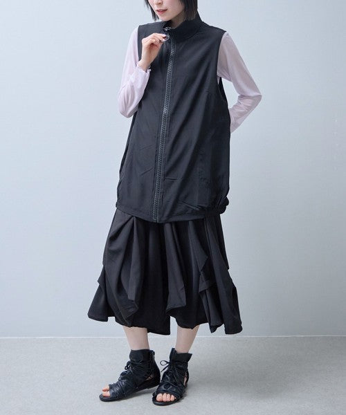 Mikonosublue Storeの黒いロングジレ。大きなリングジップと丸ポケットが特徴で、軽量でストレッチ性のあるポリスパン素材を使用したレイヤードスタイル。