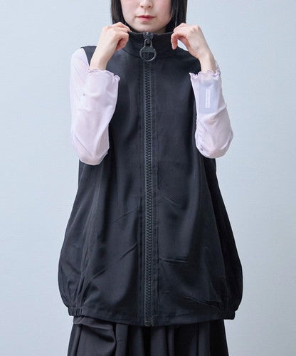 Mikonosublue Storeの黒いロングジレ。大きなリングジップと丸いポケットが特徴で、裾のゴムでコクーンシルエットを作る軽量なポリエステル混ベスト。