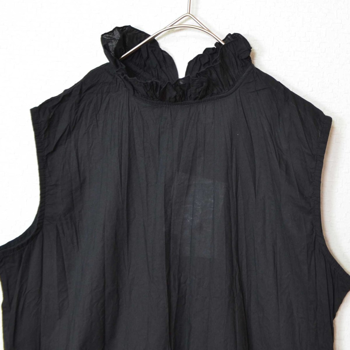 Mikonosublue Storeの黒い綿ローン素材のノースリーブブラウス。首元のフリルとクリンクル加工が特徴的なゆったりとしたデザイン。