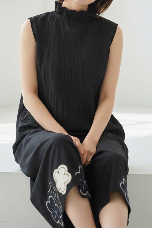 Mikonosublue Storeの黒い綿ローン素材のクリンクル加工フリルノースリーブブラウスを着用した女性