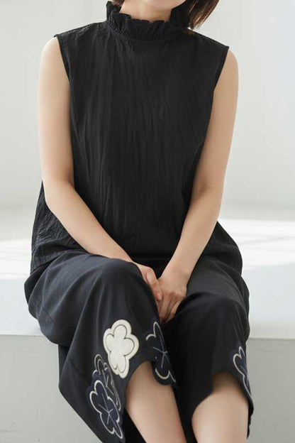 Mikonosublue Storeの黒い綿ローン素材のクリンクル加工フリルノースリーブブラウスを着用した女性