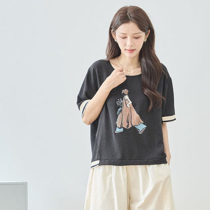 Mikonosublue Storeのファッションイラストがプリントされた黒の半袖トップス。配色リブとドロップショルダーが特徴のゆったりとしたデザイン。