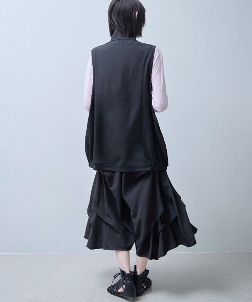 Mikonosublue Storeの黒いロングジレ。裾がゴム仕様のコクーンシルエットで、軽量なポリスパン素材を使用したレイヤードスタイル。
