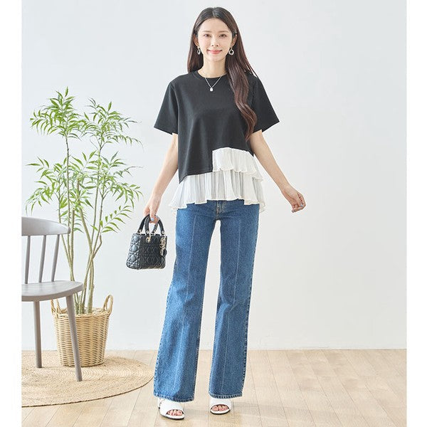 Mikonosublue Storeの黒い半袖Tシャツ。裾に白いアシンメトリーなプリーツフリルをあしらった異素材切り替えデザインで、デニムと合わせた大人カジュアルな着こなし。