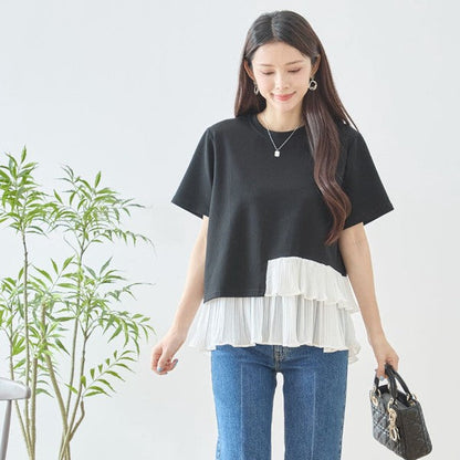 Mikonosublue Storeの黒い半袖Tシャツ。裾に白いアシンメトリーな2段ティアードプリーツフリルをあしらった異素材切り替えデザイン。