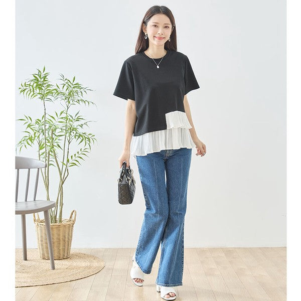 Mikonosublue Storeの黒い半袖Tシャツ。裾に白いアシンメトリーなプリーツフリルをあしらった異素材切り替えデザインで、デニムパンツと合わせたフェミニンなスタイル。