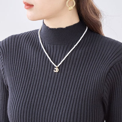 Mikonosublue Storeの黒いモックネックリブニットワンピース。伸縮性のある素材で上品なフィット感のあるデザイン。