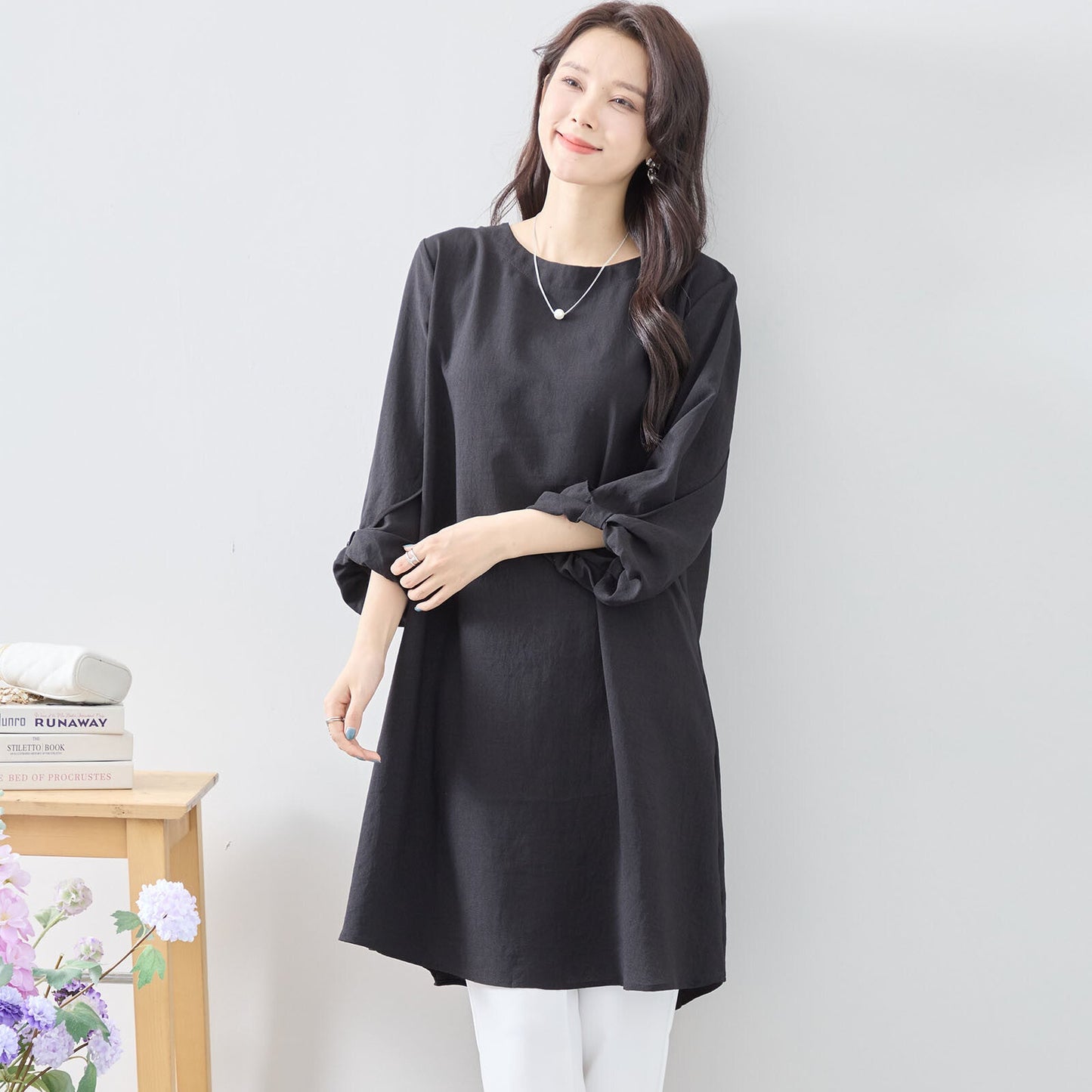 Mikonosublue Storeの袖口にリボンがあしらわれた黒のAラインチュニックワンピースを着用した女性