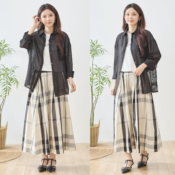 Mikonosublue Store black sheer long-sleeve shirt with floral lace panels and a relaxed fit, worn over a white t-shirt and plaid skirt.
