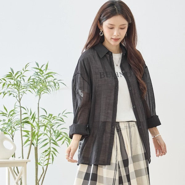 Mikonosublue Store black sheer long-sleeve shirt with lace details and a relaxed fit, worn over a white t-shirt.