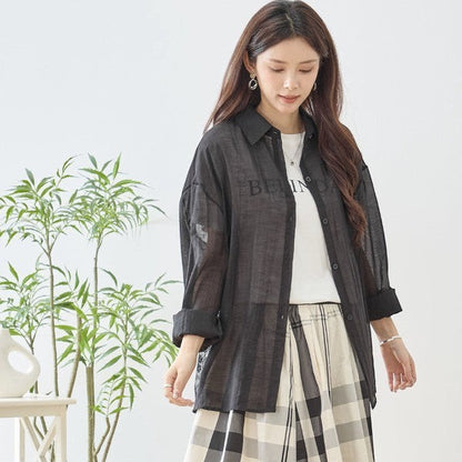 Mikonosublue Store black sheer long-sleeve shirt with lace details and a relaxed fit, worn over a white t-shirt.