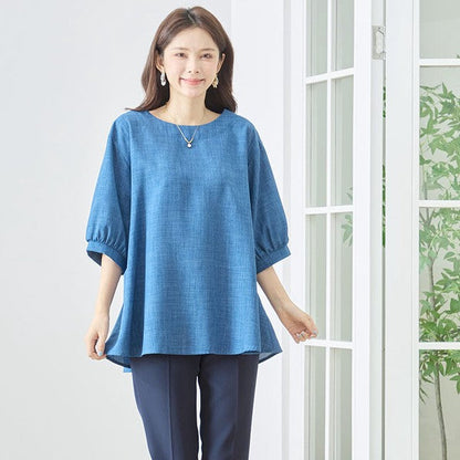 Mikonosublue Storeの青いAライントップス。5分袖でゆったりとしたシルエットが特徴の体型カバーできる夏用ブラウスを着用した女性。
