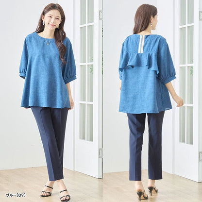 Mikonosublue Storeのバックフリルが特徴的な青い5分袖Aライントップス。ゆったりとしたシルエットで二の腕をカバーし、後ろ姿にファスナーと2段フリルをあしらったフェミニンな夏用ブラウス。