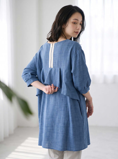 Mikonosublue Storeのバックフリルとファスナーが特徴的な青いAラインの5分袖トップスを着用した女性