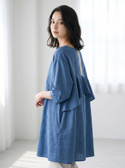 Mikonosublue Storeのバックフリルが特徴的なブルーの5分袖Aライントップスを着用した女性のバックスタイル