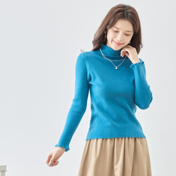 Mikonosublue Storeのブルーのリブニットプルオーバー。首元と袖口にフリルがあしらわれたハイネックデザインで、女性らしいシルエットが魅力の秋冬用インナー。