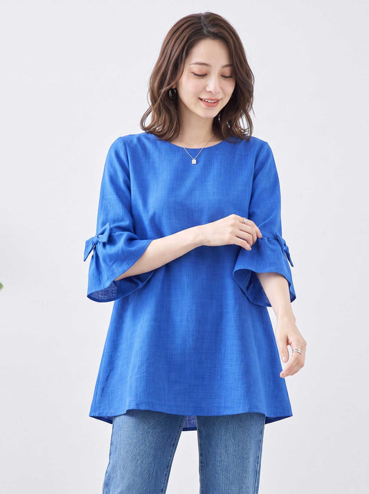 Mikonosublue Storeの青い袖リボン付きAラインチュニックブラウスを着用した女性