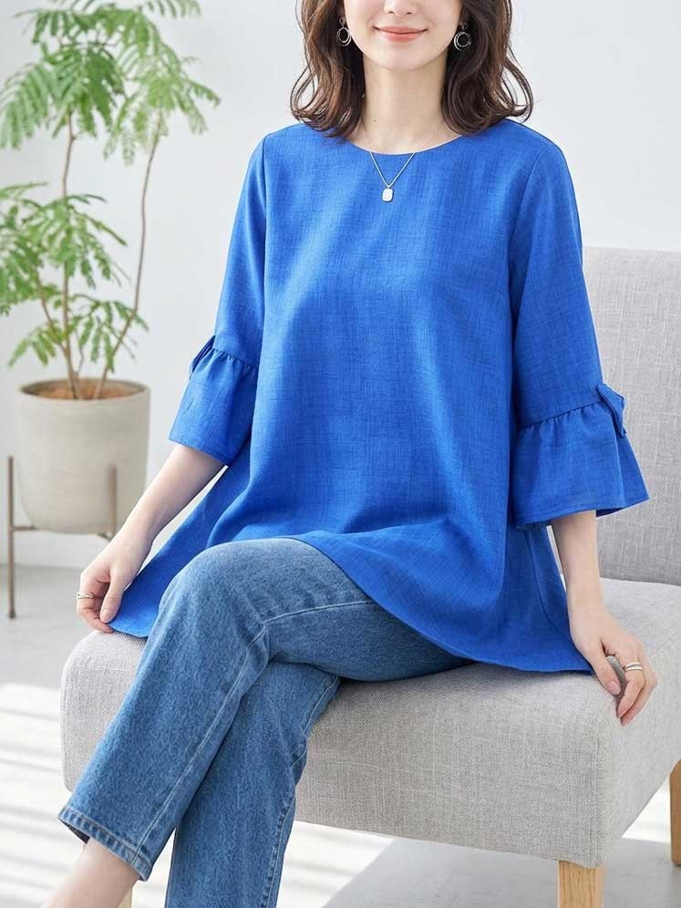 Mikonosublue Storeの鮮やかなブルーの七分袖チュニック。袖口のリボンとふんわりとしたAラインシルエットが特徴で、デニムと合わせたきれいめカジュアルなスタイル。