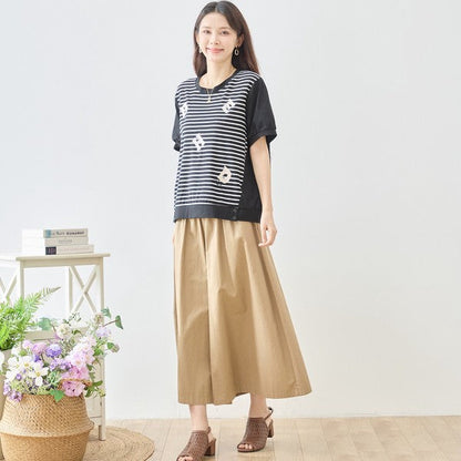 Mikonosublue Storeのアルファベット刺繍入りボーダー切り替えTシャツを着用した女性。ゆったりとしたシルエットで体型カバーも叶うカジュアルな半袖トップス。