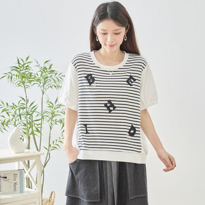 Mikonosublue Storeのアルファベット刺繍入りボーダー切り替え半袖Tシャツ。ゆったりとしたシルエットで体型カバーも叶う綿混ストレッチ素材。