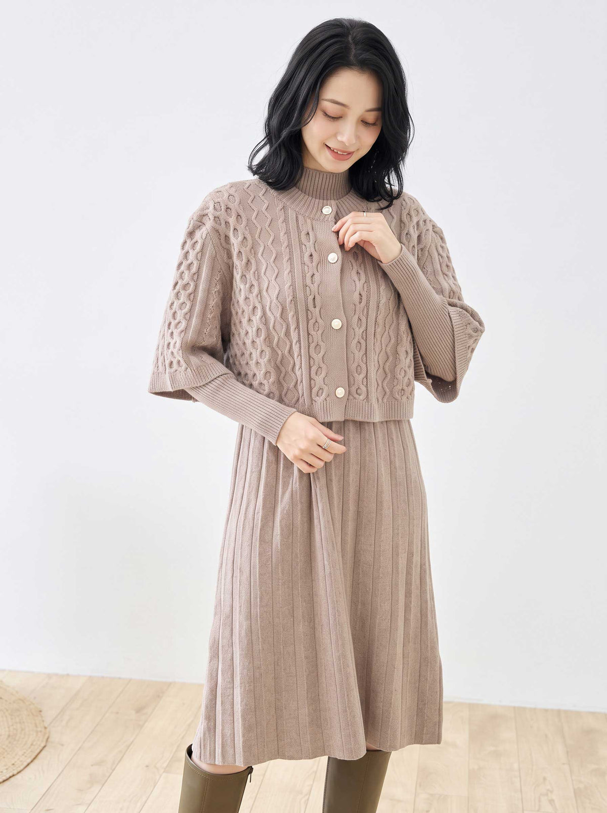 Mikonosublue Storeのベージュのケーブル編みボレロとリブニットワンピースのセットアップを着用した女性