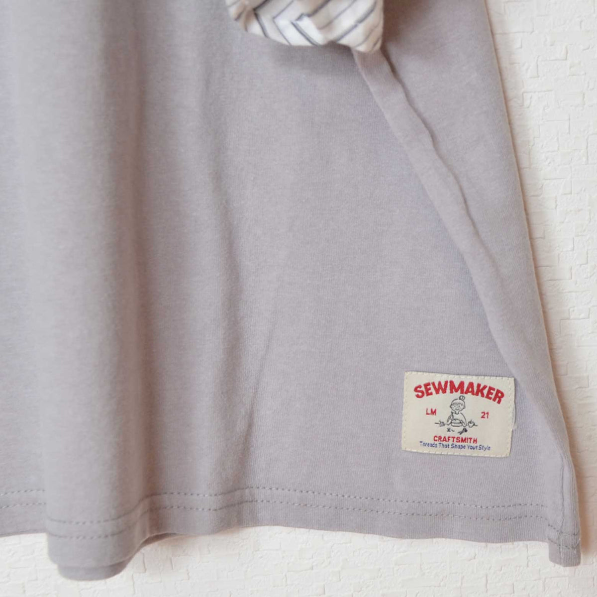 Mikonosublue Storeのケミカル加工天竺Tシャツ。裾にSEWMAKERのロゴタグが付いた綿100%のカジュアルな半袖トップス。